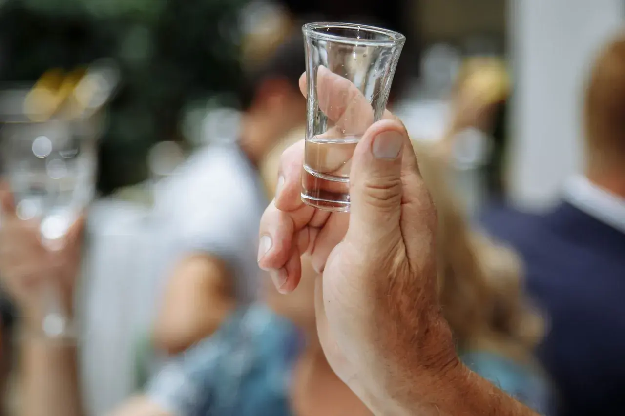 Dłoń trzyma kieliszek z alkoholem. Czy po whisky jest kac? Zależy od ilości i jakości trunku.