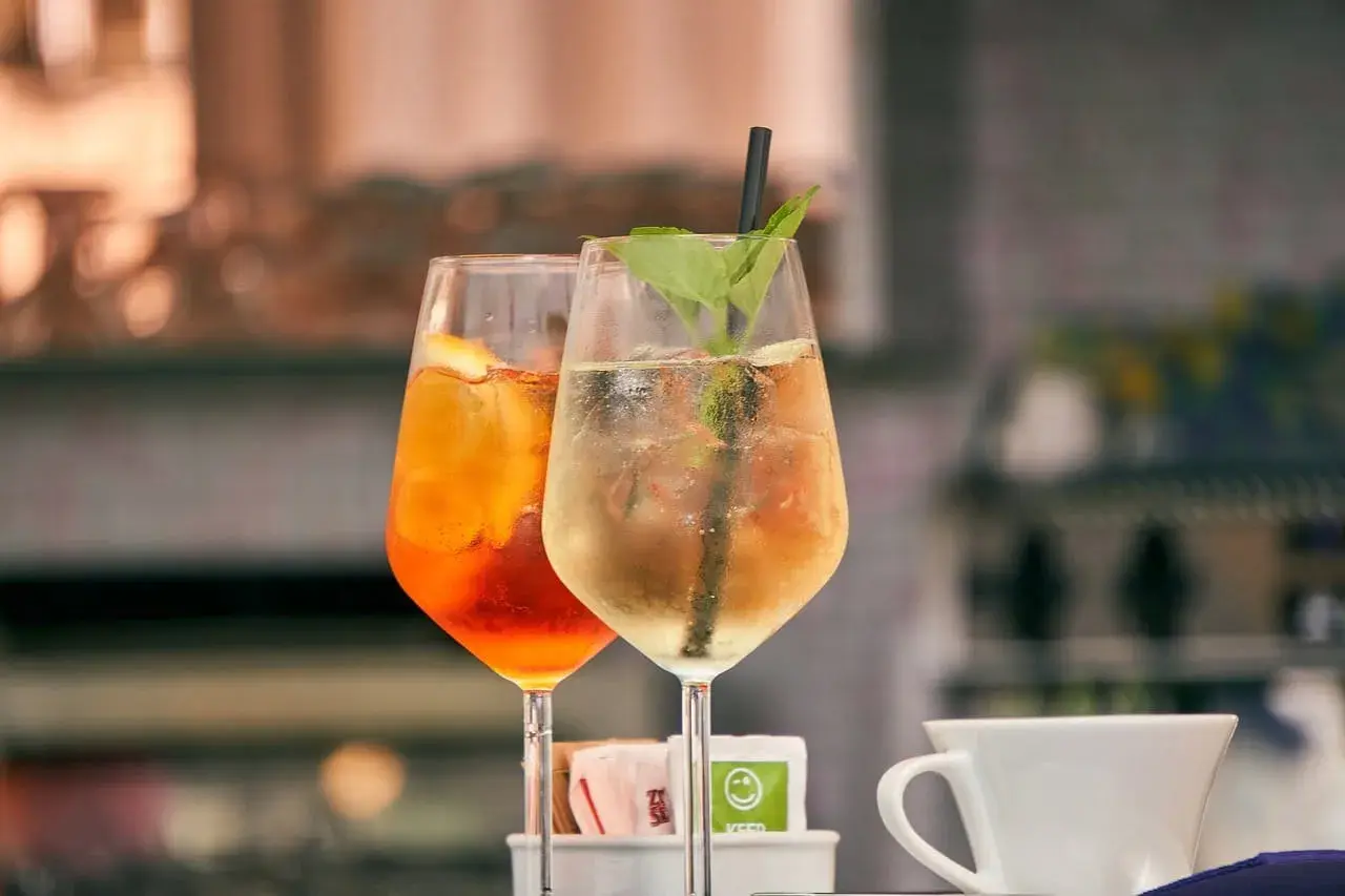 Dwa drinki z lodem i owocami, jeden pomarańczowy, drugi jasny. Czy warto kupować drogie giny do drinków mieszanych z owocami?