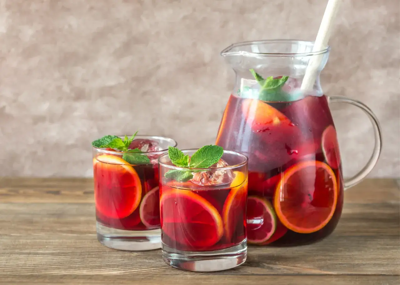 Domowa sangria z owocami i winem czerwonym: orzeźwiający napój w dzbanku i szklankach, ozdobiony plasterkami cytrusów i miętą.