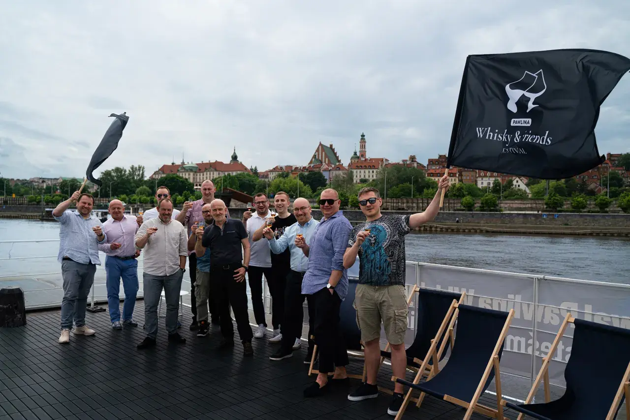 Grupa mężczyzn świętuje na statku, unosząc kieliszki. Czy warto inwestować w whisky kolekcjonerską? Portfel inwestycyjny 2026.