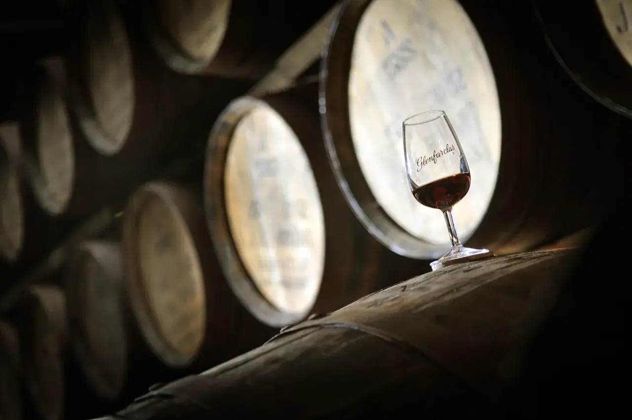 Kieliszek whisky Glenfarclas na beczce, symbol najlepszych technik leżakowania whisky finiszowanie w beczkach po sherry.