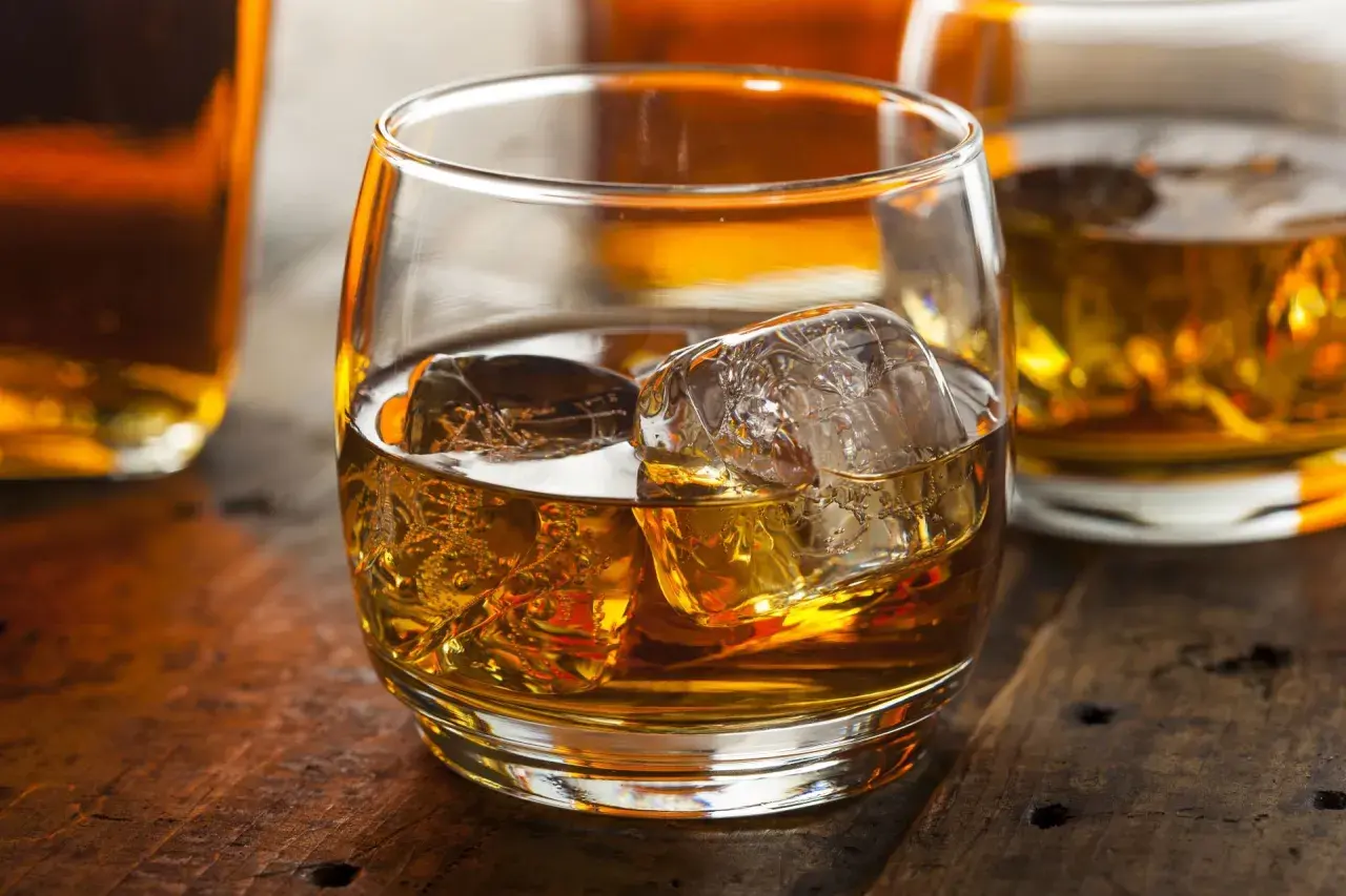 Szklanka whisky z lodem na drewnianym stole. Dowiedz się o różnicy między whisky szkocką a kanadyjską i irlandzką wymogi prawne.