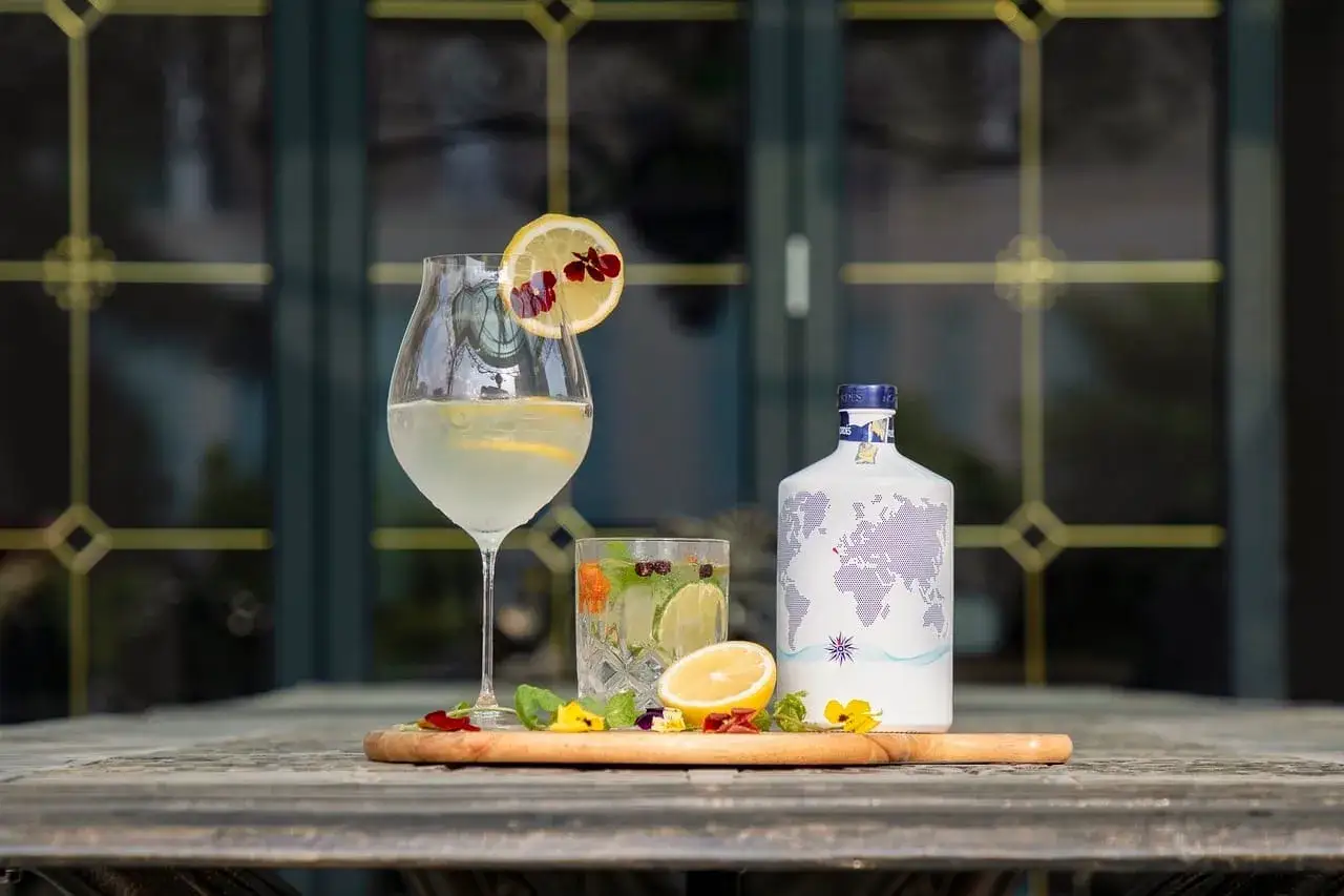 Jak przygotować infuzowany alkohol, np. wódkę o smaku chilli? Na stole stoją drinki, cytryny, zioła i butelka z mapą świata.