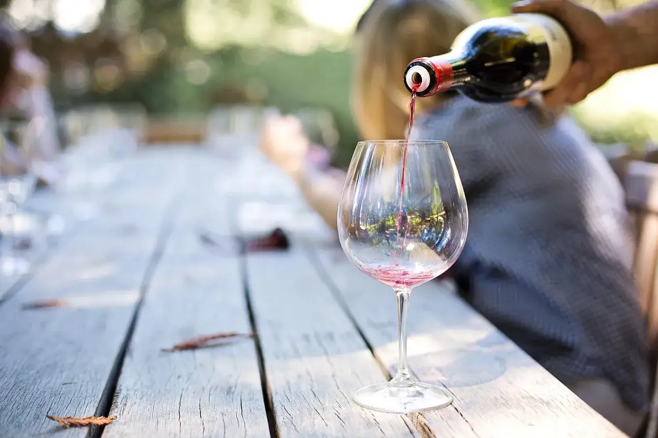 Czerwone wino nalewane do kieliszka, zapowiedź degustacji metodą 5S: patrz, kręć, wąchaj, smakuj, delektuj się.