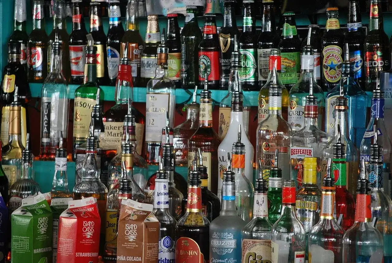 Rząd butelek alkoholu, od whisky po gin. Zastanawiasz się, jak sprawdzić, czy stara butelka whisky z barku nadaje się do picia? Spójrz na kolor i zapach.