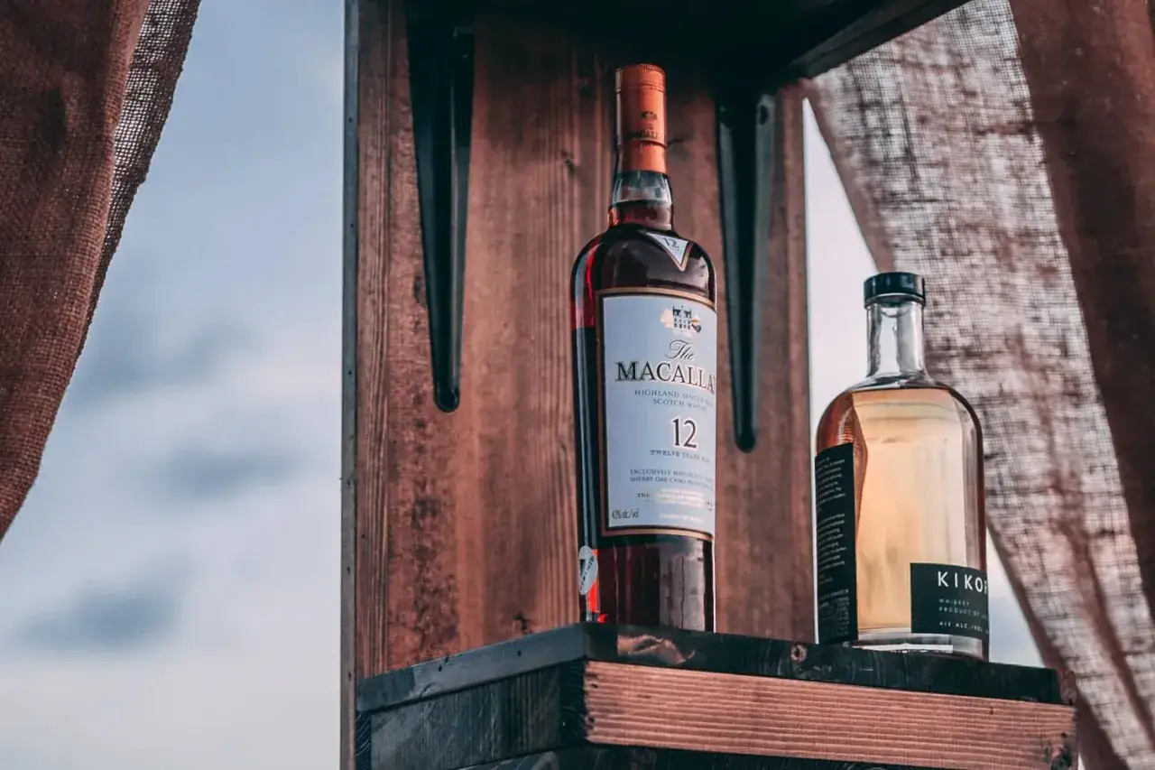 Dwie butelki whisky na drewnianej półce. Zastanawiasz się, jak sprawdzić, czy stara butelka whisky z barku nadaje się do picia?