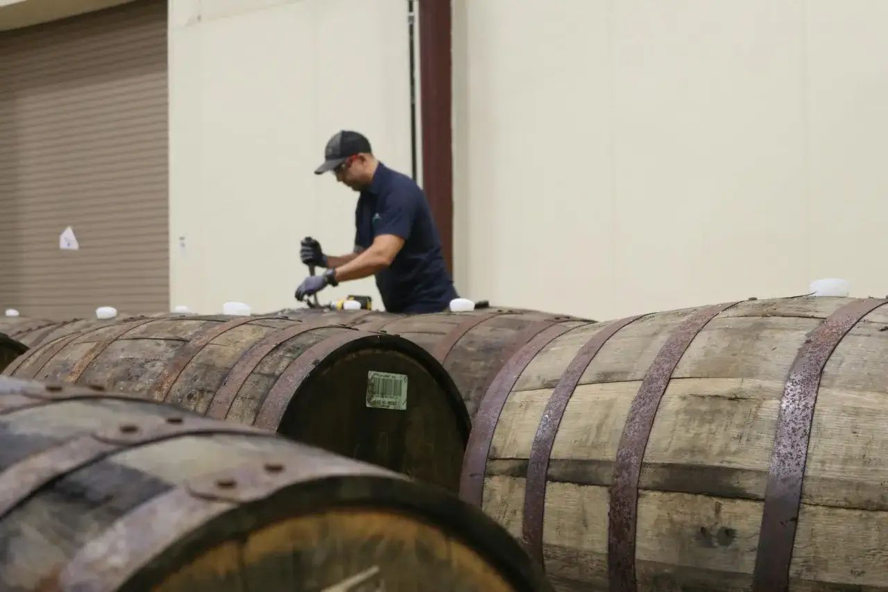 Pracownik w piwnicy sprawdza beczki, zastanawiając się, czy warto leżakować piwa rzemieślnicze (barrel aged).