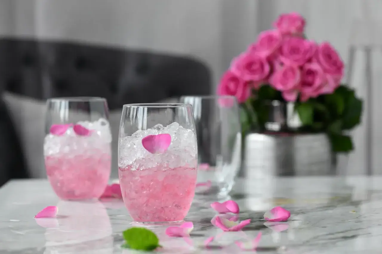 Różowe drinki z płatkami róż i lodem, idealne do prosecco. Bukiet róż w tle.