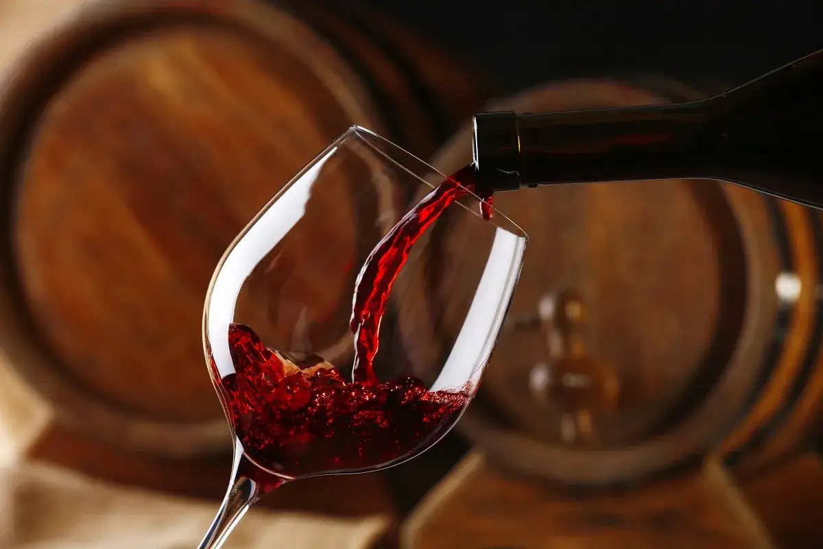 Czerwone wino nalewane do kieliszka. Różnica między winem wytrawnym a półwytrawnym to zawartość cukru.