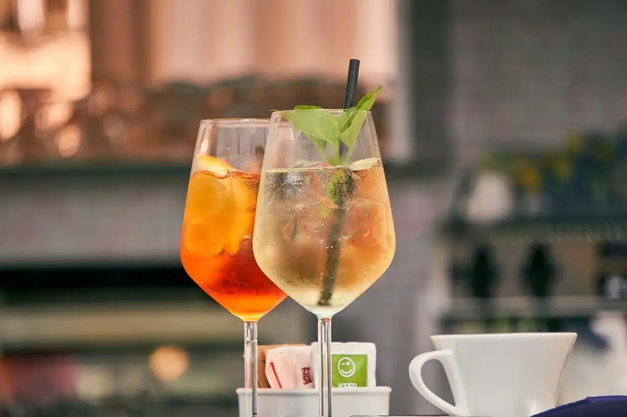 Dwa orzeźwiające drinki: jeden pomarańczowy, drugi z miętą, idealne na letnie popołudnie. Może to być gin z tonikiem.