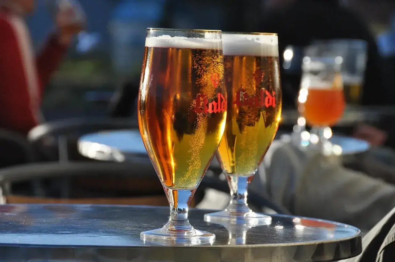 Dwa kieliszki złocistego piwa z pianką, idealne do degustacji aromatów i goryczki. To najlepsze techniki chmielenia na zimno (dry hopping).