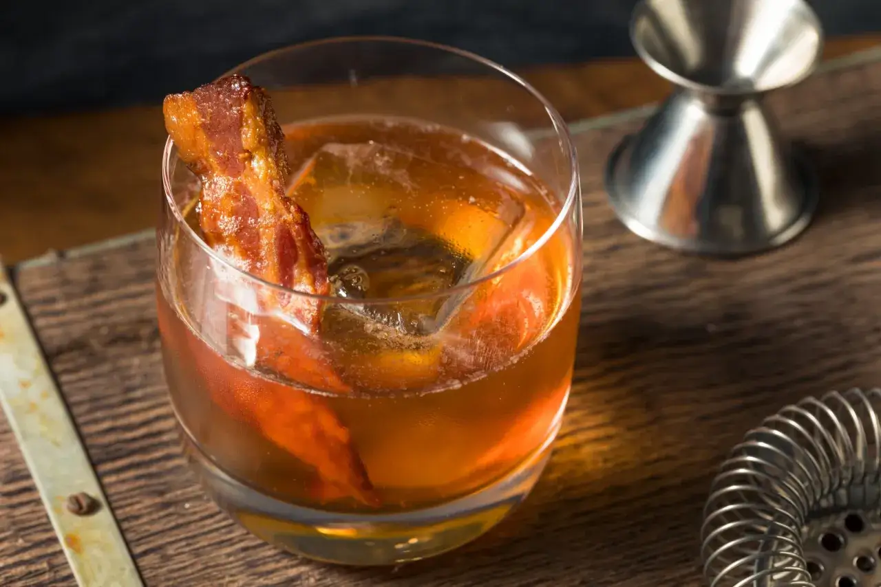 Whisky z boczkiem, czyli jak zrobić infuzowaną whisky z boczkiem (fat washing) techniką barmańską. Drink z lodem i plasterkiem boczku.