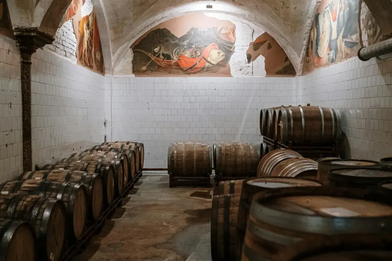 Piwnica z beczkami, gdzie dojrzewa whisky. Ściany zdobią stare freski, a w powietrzu unosi się zapach drewna i alkoholu. Metaliczny posmak i pieczenie mogą być objawami niskiej jakości whisky zbożowej.