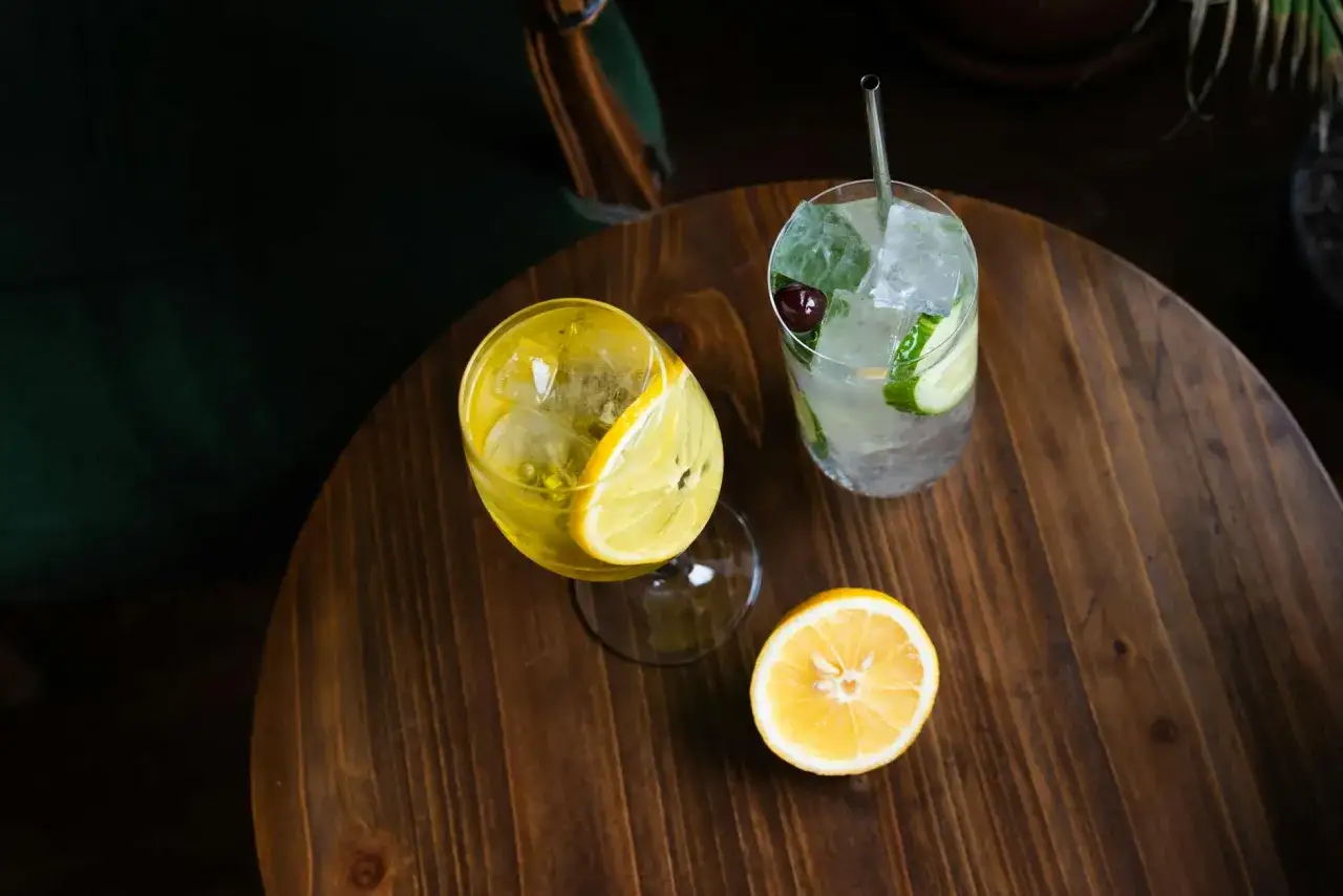 Dwa orzeźwiające drinki z cytryną i ogórkiem na drewnianym blacie. Skutki przegrzania składników podczas muddlowania owoców mogą wpłynąć na smak.