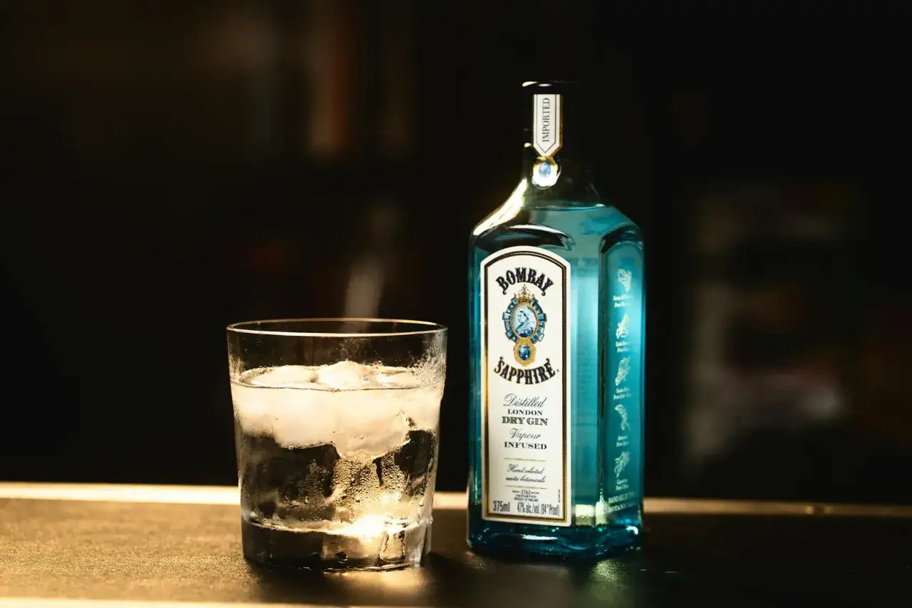 Szklanka z lodem i butelka Bombay Sapphire. Idealny zestaw na orzeźwiający gin z tonikiem.